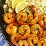 Garlic paprika shrimp served with lemon slices and cauliflower rice in a cast iron skillet.